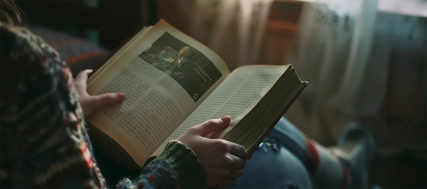 A person relaxing on a couch while reading a book.